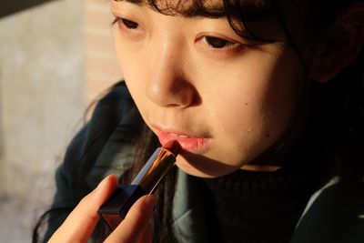 Close-up of girl applying lipstick