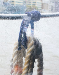 Close-up of rope hanging on metal seen through window during winter