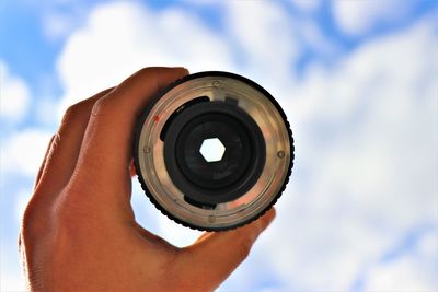 Midsection of person holding camera against sky