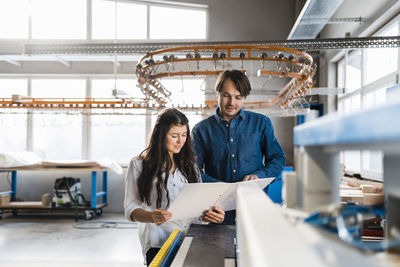 Inspector reading file while standing by colleague at industry