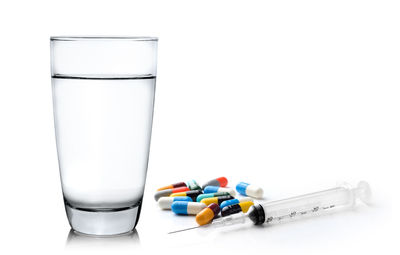 Close-up of medicine with water against white background