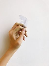 Close-up of hand holding paper against white background