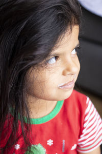 Close-up of cute girl with milk mustache looking away