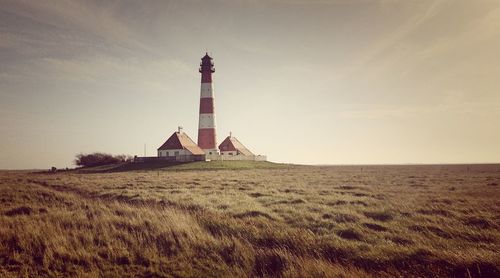 Lighthouse on field against sky