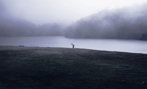 Scenic view of lake against sky during foggy weather