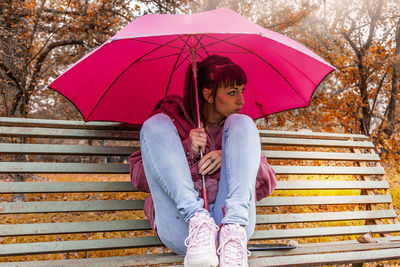 Young woman sitting on umbrella in rain