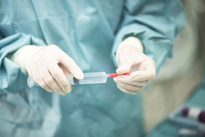 Midsection of doctor holding syringe in hospital