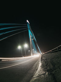 Light trails on bridge against sky at night