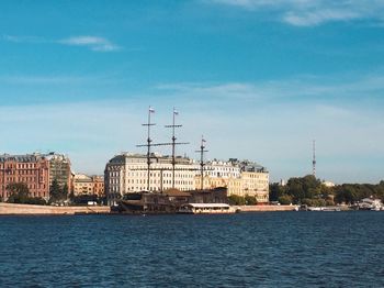 Buildings by river against blue sky