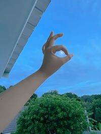 Low angle view of person hand against sky