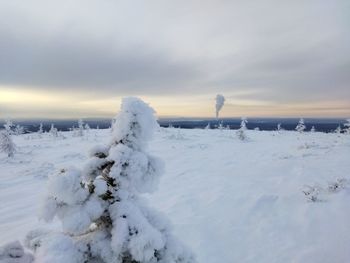 Snow covered landscape against sky during sunset