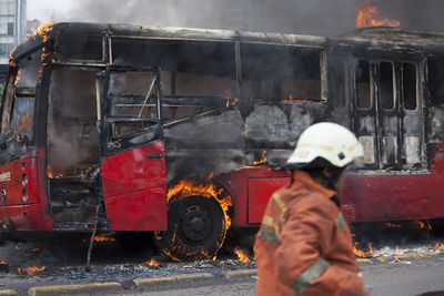 Firefighter standing by bus burning on street