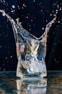 Close-up of water splashing on glass against black background