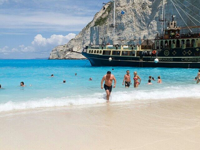 beach, sea, water, large group of people, lifestyles, leisure activity, building exterior, architecture, shore, built structure, sand, vacations, men, person, tourist, mixed age range, sky, enjoyment, tourism