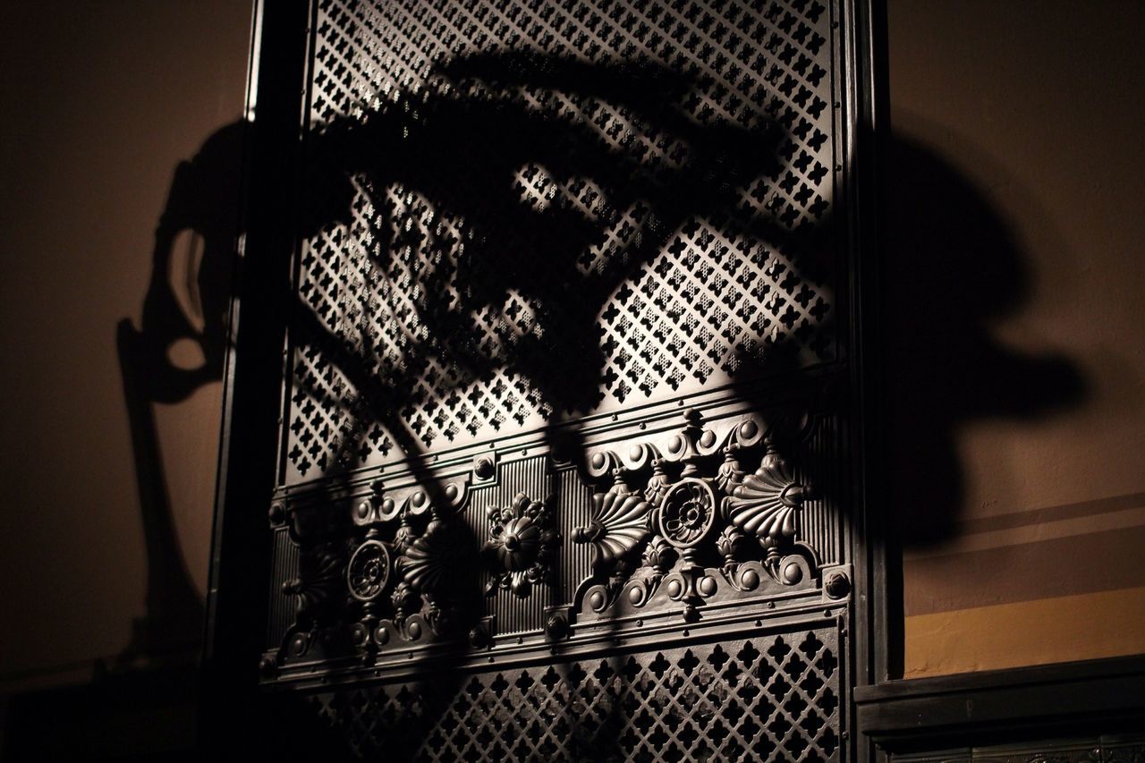 indoors, shadow, wall - building feature, metal, pattern, home interior, design, bicycle, sunlight, no people, close-up, silhouette, metallic, built structure, absence, wall, window, metal grate, protection, safety