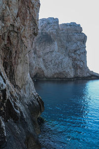 Rock formation by sea against sky