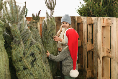 Rear view of woman standing by tree trunk