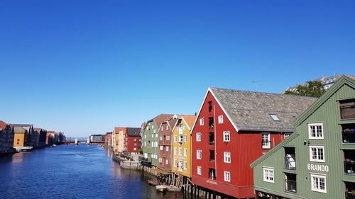 Canal amidst buildings against blue sky