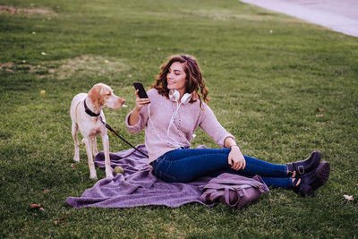 Woman with dog sitting on field