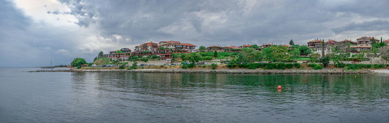 Panoramic view of sea by buildings against sky