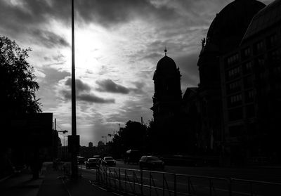 Cars on street amidst buildings against sky at dusk