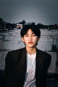 Portrait of young man standing against wall