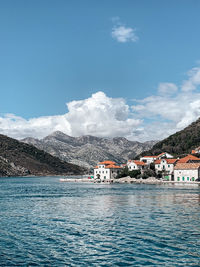 Buildings by sea against blue sky