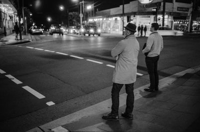 Rear view of people walking on road at night