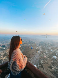 Rear view of woman looking at sea against sky during sunset