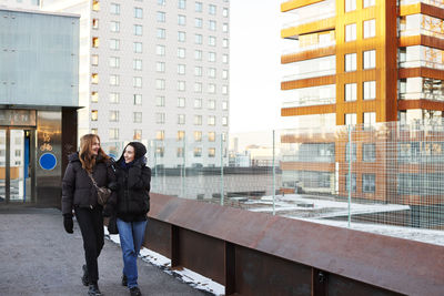 Smiling female couple walking in modern neighborhood