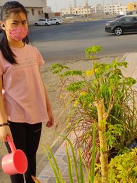 Full length of woman standing by car against plants