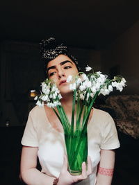 Close-up of woman holding flower bouquet against wall