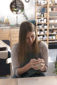 Beautiful young woman sculpts a mug out of clay. pottery workshop class.