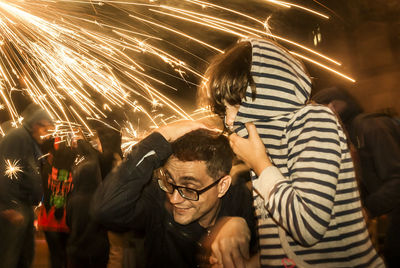 People standing by illuminated street at night