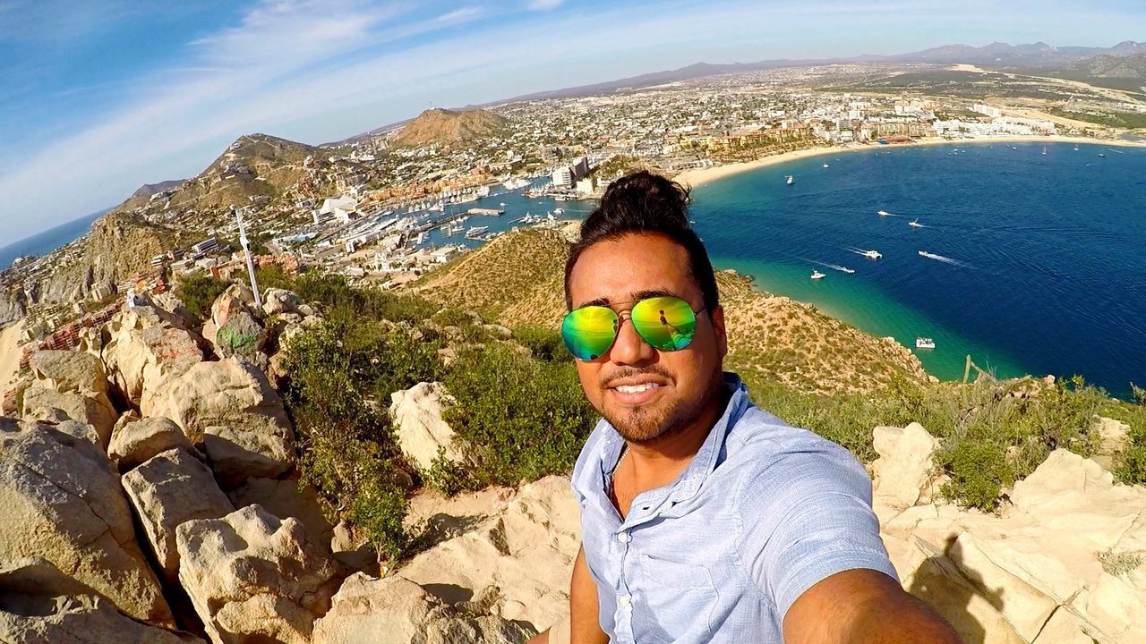 PORTRAIT OF SMILING YOUNG MAN ON CLIFF