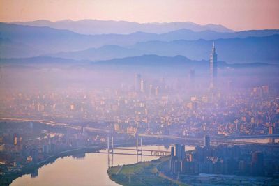 Aerial view of cityscape against mountains during foggy weather