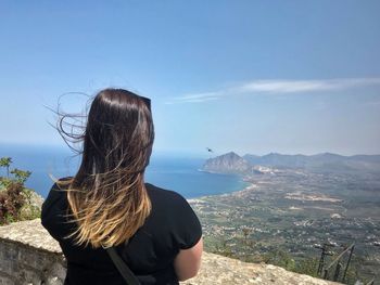 Rear view of woman standing by mountain against sky