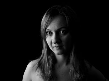 Portrait of woman against black background