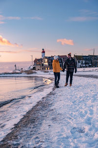 Rear view of women walking on snow covered land