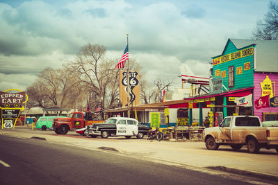 Cars on city street against cloudy sky