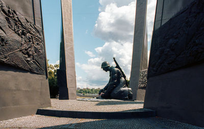 Statue by historic building against sky