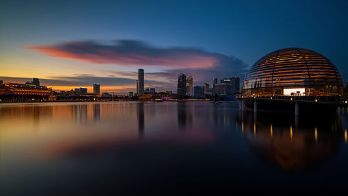 Reflection of buildings in city at sunset