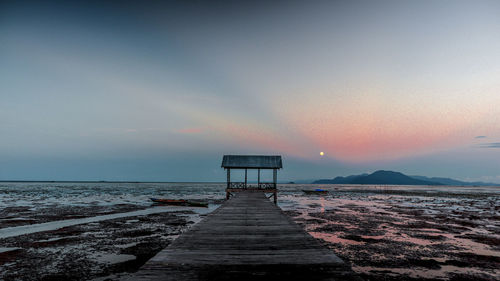 Pier over sea against sky during sunset