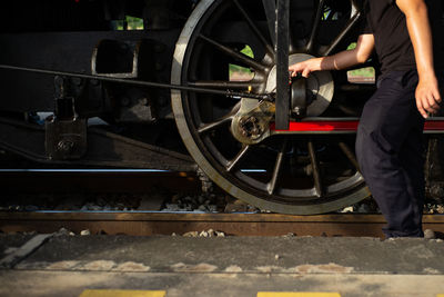 Closeup worker dropping the lubricant oil into the steel wheel of vintage train locomotive. repair