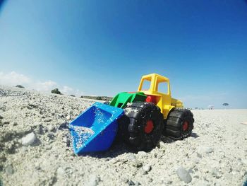 Close-up of toy car at beach against blue sky