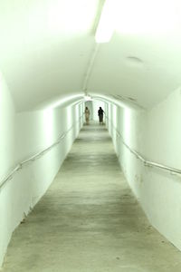 Rear view of person walking in illuminated tunnel