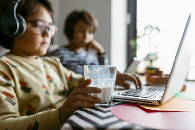 Rear view of man and woman using mobile phone on table