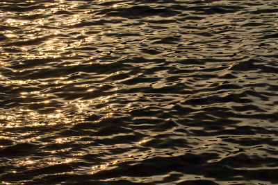 A nature background image of the surface of the ocean with golden glow of an orange sunset 