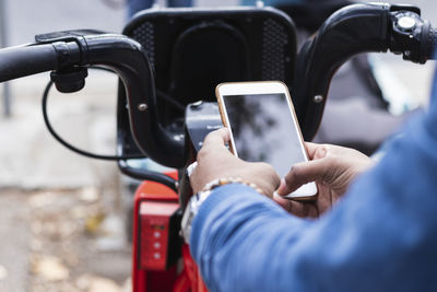 Hands of man using smart phone for renting bicycle at parking station