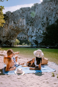 Full length of couple sitting on beach